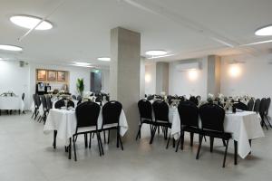 a banquet hall with white tables and black chairs at מלון ברגר - למגזר החרדי in Tiberias