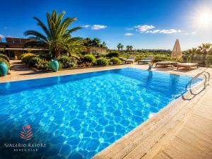 a swimming pool at a resort with palm trees at Valerio Resort beach club in Margherita di Savoia