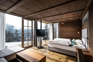 a bedroom with a bed and a balcony with a television at Ansitz Velseck-Residence Hotel in Tires