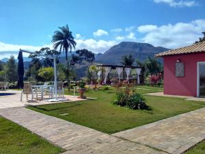 a garden with a table and chairs and mountains in the background at Pousada Princesa Do Vale in Belo Vale