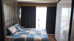 a bedroom with a bed and a large window at Ruby Apartment #47 in Kejayan
