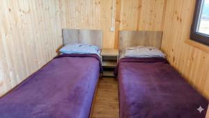 Zwei Betten in einem kleinen Zimmer mit Holzwänden in der Unterkunft Sevan - Tsovazard Wooden House in Tsovazard