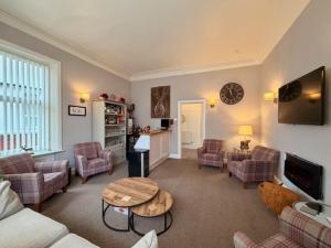 a living room with couches and a table and a tv at Avenue Guest House in Blackpool