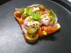 a piece of bread with vegetables on a black plate at RADHA Homestay in Mathura