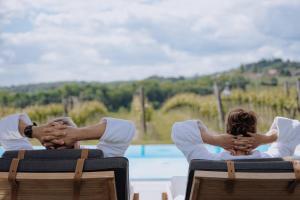 a couple holding hands while sitting in chairs by a pool at Winzerhof - Deutsch Haseldorf in Deutsch Haseldorf