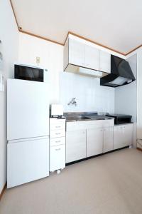 a white kitchen with a sink and a refrigerator at Beppu Paw House in Beppu