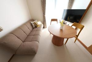 a living room with a couch and a table at Beppu Paw House in Beppu