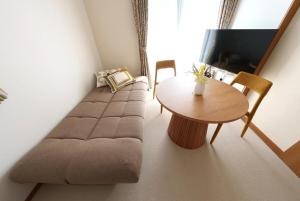a living room with a couch and a table at Beppu Paw House in Beppu