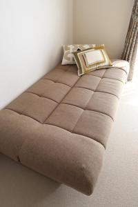 a brown bed in a corner of a room at Beppu Paw House in Beppu +40 photos