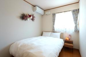 a bedroom with a white bed and a window at Beppu Paw House in Beppu