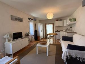a living room with a white couch and a tv at Le Châtaignier in Faveyrolles