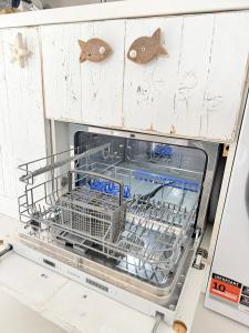an open dishwasher with dishes inside of it at Precioso bungalow con piscina en 1a Linea Playa in Denia