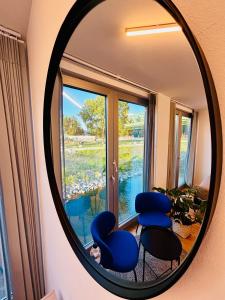 a mirror reflecting a room with blue chairs and a window at Sundeck botel - party boat in Bratislava