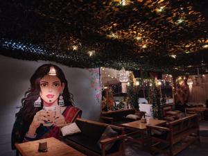a painting of a woman holding a drink in a restaurant at Wabi Sabi Hostel in Kasol