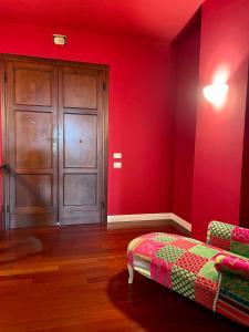 a red room with a bed and a wooden door at Villa G in Ravenna