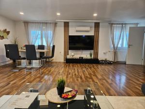 a living room with a wooden floor and a large screen tv at Modernes Haus nahe See mit Garten & Terrasse in Velm