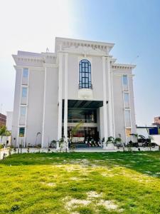 a large white building with a lawn in front of it at The RK Resort in Siwān +4 photos