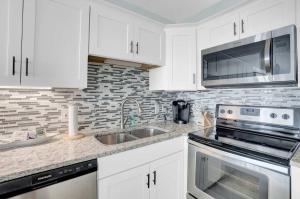 a kitchen with white cabinets and a sink and a microwave at Corner on Romar 706 in Orange Beach