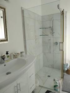 a white bathroom with a shower and a sink at Tulip Apartment in Cambridge