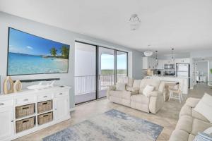 a white living room with a large tv on the wall at Corner on Romar 706 in Orange Beach +59 photos