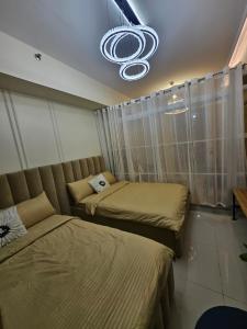 a bedroom with two beds and a chandelier at Alder Wind Staycations Tagaytay in Kaybagal +1 photo