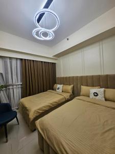 a bedroom with two beds and a chandelier at Alder Wind Staycations Tagaytay in Kaybagal