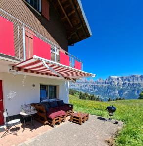 a house with a patio with a grill and mountains at Ferienwohnung Tschudiboden in Flumserberg