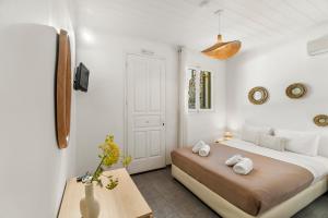 a white bedroom with a bed and a table at LausAndros Suites in Andros