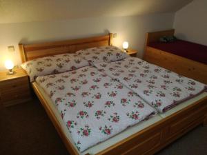 a bed with a white blanket with flowers on it at Apartmán u Kovářů in Kašperské Hory