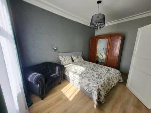 a bedroom with a bed and a chair and a mirror at Keskallee Charm in Kohtla-Järve