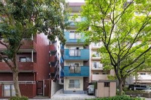 an apartment building with blue balconies and trees at 第2舞鶴ハイツ in Fukuoka