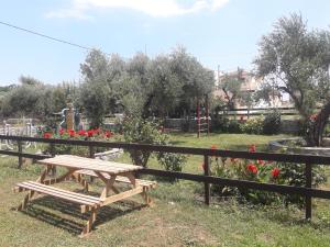 a wooden picnic table in a garden with red flowers at olivensun apartment 6 in Gythio