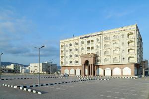 a large white building in a parking lot at Al Sahwa Residency in Ţāqah