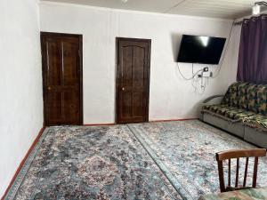 a living room with a couch and a television at Sunrise Panorama in Bokonbayevo