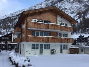 a large building with a balcony in the snow at Haus Mondelli in Saas-Almagell