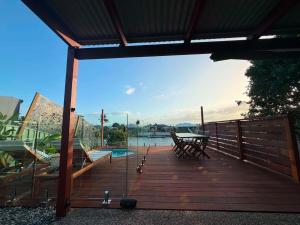 a wooden deck with a table and a view of the water at Pet Friendly - Plunge Pool Canal Sunset View - Private Jetty in Bongaree