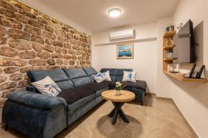 a living room with a blue couch and a stone wall at Apartmani Žunić in Pag