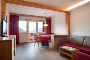 a living room with a red couch and a table at Hotel Appartement Inge in Tirolo