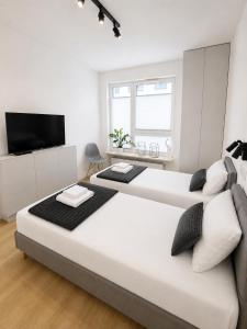 a white bedroom with two beds and a tv at APARTAMENT 4 bed 2 room WARSAW in Warsaw