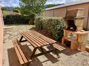 a wooden picnic table and a grill in a yard at location verdon in Les Salles-sur-Verdon