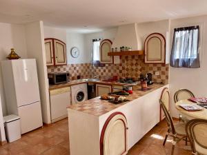 a kitchen with a white refrigerator and a table with chairs at location verdon in Les Salles-sur-Verdon