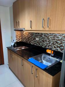 a kitchen with a sink and wooden cabinets at Shell Residences in Sampong
