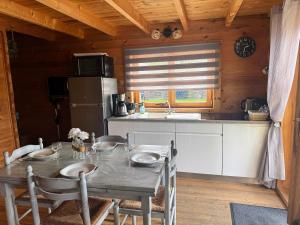a kitchen with a table with chairs and a refrigerator at " domaine des chevrettes chalet cosy au cœur des châteaux " in Cour-Cheverny