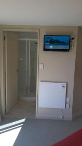 a room with a white wall with a tv on the wall at Pukeko on Bay in Tauranga