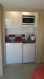 uma pequena cozinha com um micro-ondas e um lavatório em Pukeko on Bay em Tauranga