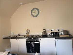 eine Küche mit einem Herd und einer Uhr an der Wand in der Unterkunft The Old Coach House in Eyemouth