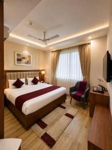 a hotel room with a large bed and a chair at Hotel Lotus Palace in Lucknow