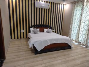 a bedroom with a bed with a striped wall at Angel Garden Farmhouse in Noida