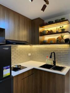 a kitchen with a sink and a black refrigerator at SM Bicutan Staycation by Urban Suite in Manila