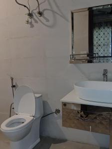 a bathroom with a white toilet and a sink at Angel Garden Farmhouse in Noida +10 photos